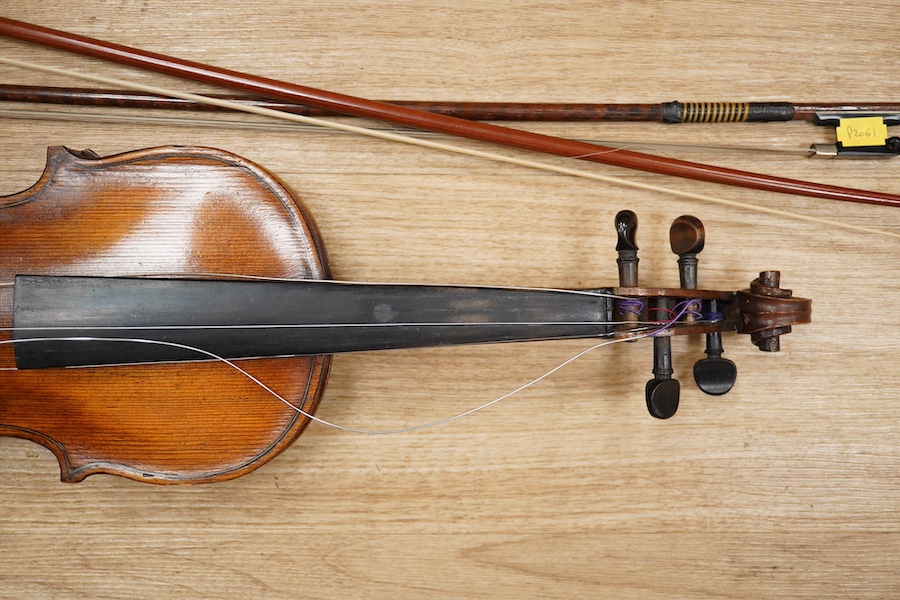 A late 19th century German violin, body 35cm long, and two bows. Condition - poor to fair.